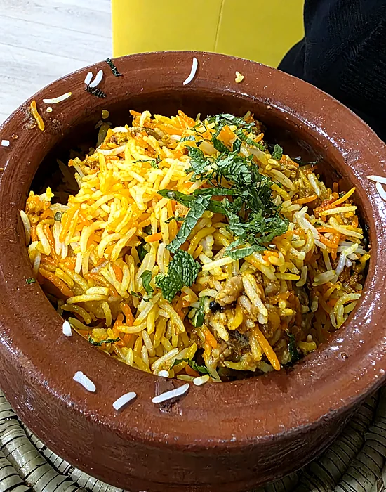 Biryani in a clay matka pot topped with fresh mint